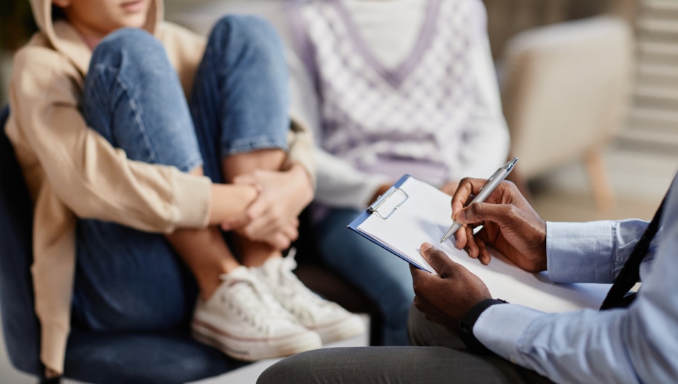 A girl and a woman in a therapy session with a therapist taking notes