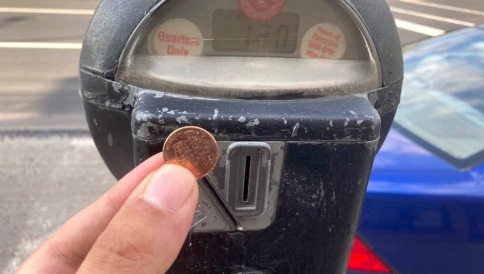 Someone putting a penny into an Upper Darby parking meter