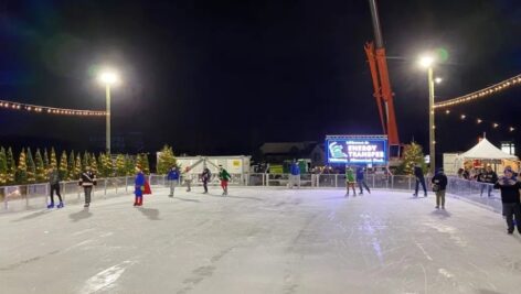Skaters on an outdoor ice rink at night