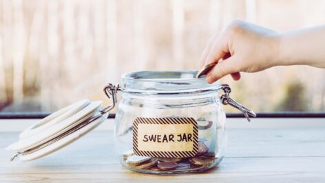 hand putting coin into swear jar