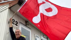 Carl Henderson waves a giant Phillies flag outside his Havertown business