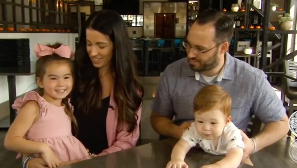 family sits at table in their restaurant Dom & Mia's