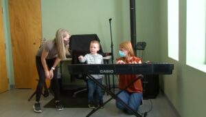 two teachers and a kid behind an electric piano