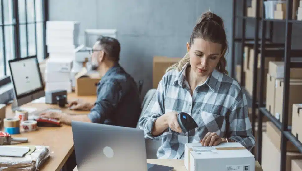 A man and woman at computers in an office running an E-Commerce business.