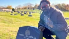 Hakeem Thomas Sr., superintendent of Eden Cemetery in Collingdale, Pa., poses by the headstone of Negro Leagues pitcher Daniel McClellan.