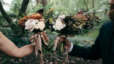 A wedding for nature lovers as two people hold wedding bouquets in the forest