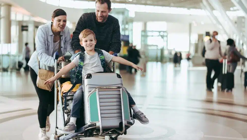 Parents move a luggage trolley with their son at the airport