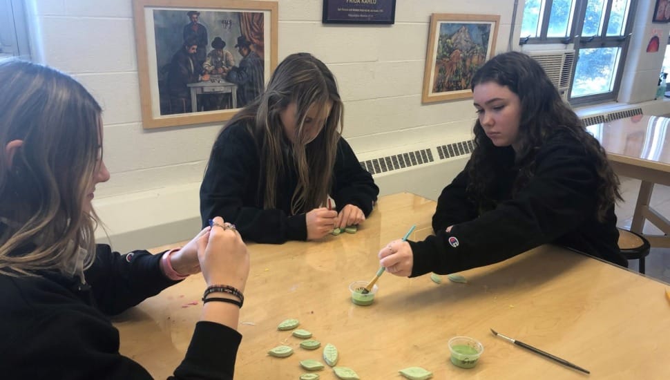 Three high school girls from Archbishop John Carroll High School paint leaves for a mosaic scene