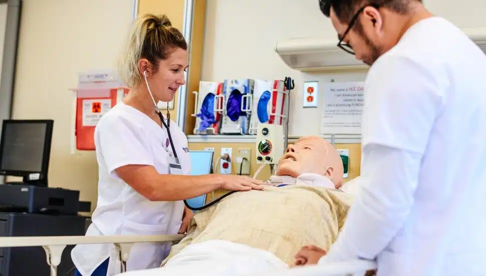 A nursing student works with a mock patient in Neumann's nursing class.