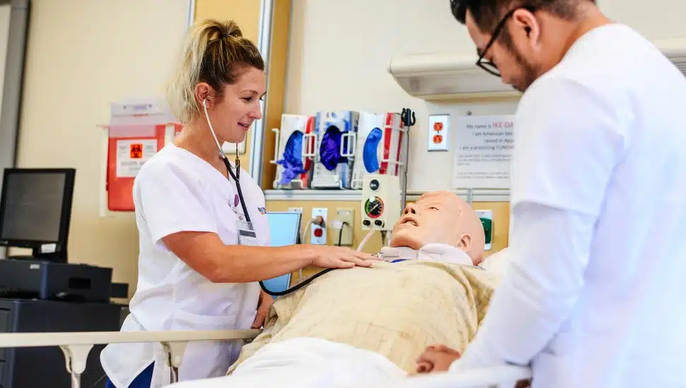 A nursing student works with a mock patient in Neumann's nursing class.