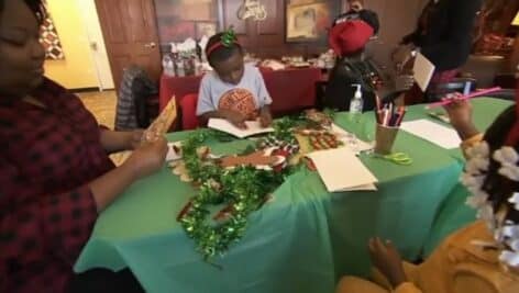 Children and adults gather around the table to make holiday cards for seniors in Upper Darby