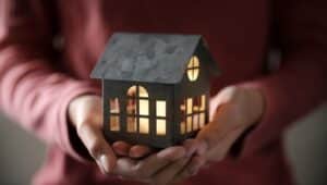 A pair of hands holding a lit model house