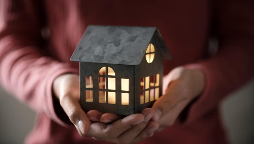 A pair of hands holding a lit model house