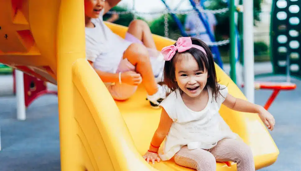 Two little girls coming down a slide