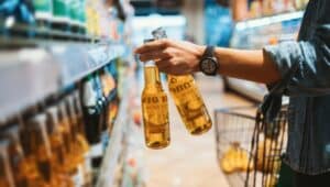 A woman's hands grasp two bottles of alcohol while shopping in a store