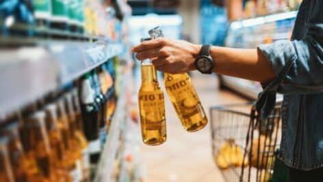 A woman's hands grasp two bottles of alcohol while shopping in a store