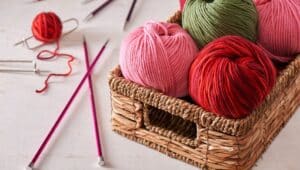 Skeins of yarn in a basket with knitting needles