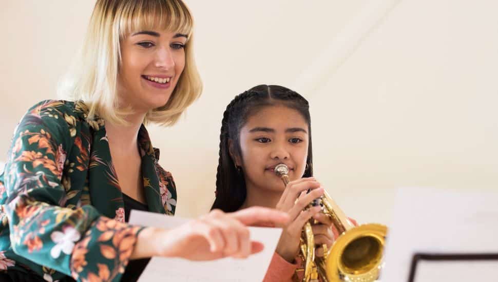 Teacher Helping Female Student To Play Trumpet In Music Lesson