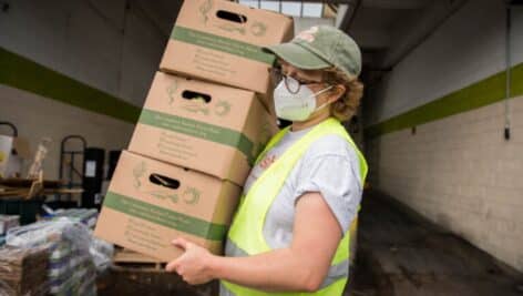 A Share Food program worker carries boxes.