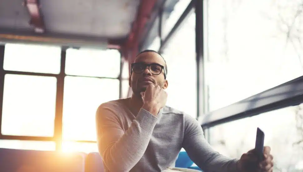 Man in a contemplative mood sitting at a table with the sun behind him
