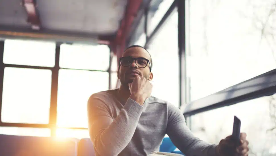 Man in a contemplative mood sitting at a table with the sun behind him