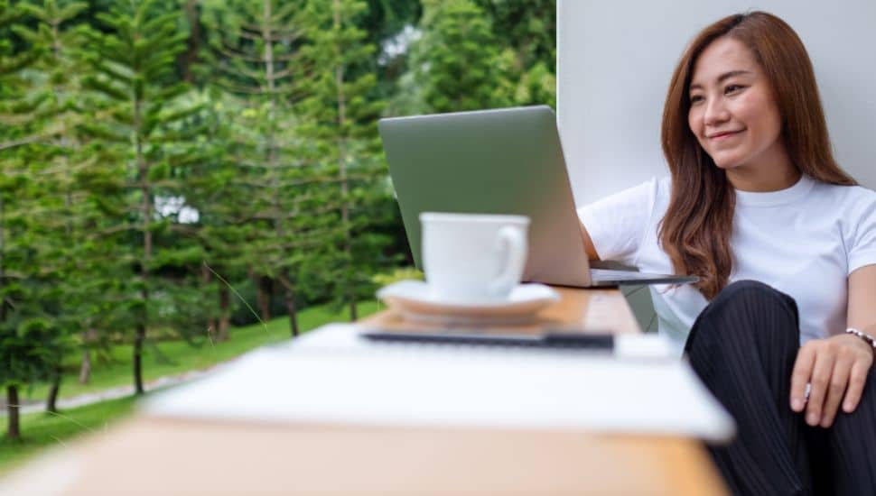 A young woman using and working on laptop computer in the outdoors