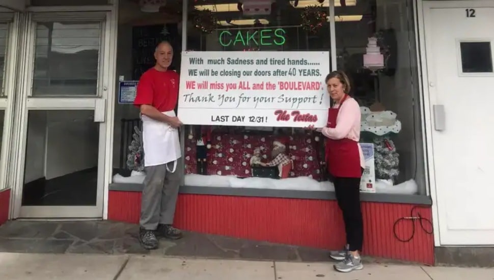 Janis and Lou Testa holding a sign about their closing outside their Brookline Blvd. bakery