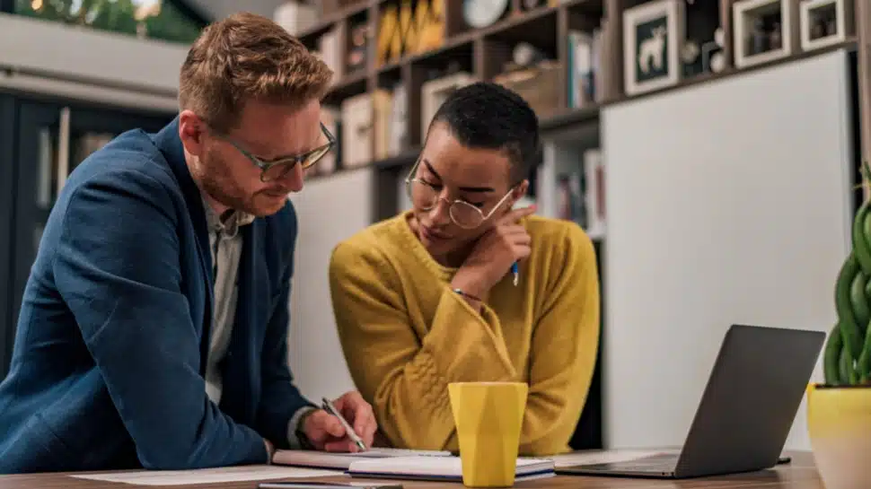 A mentor and a small business owner look over plans as the mentor offers guidance