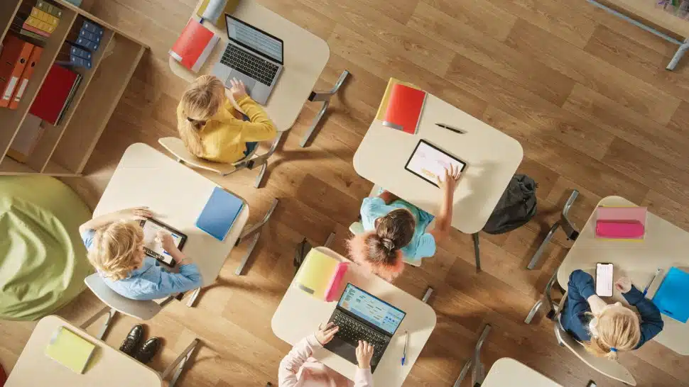 Children sitting at their school desks using personal computers and digital tablets