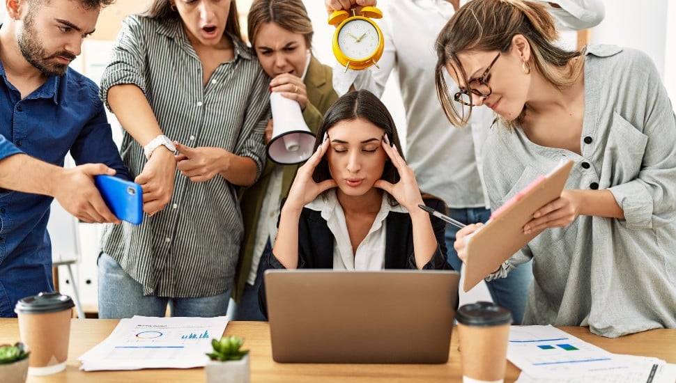 Group of business workers screaming to stressed partner at the office.