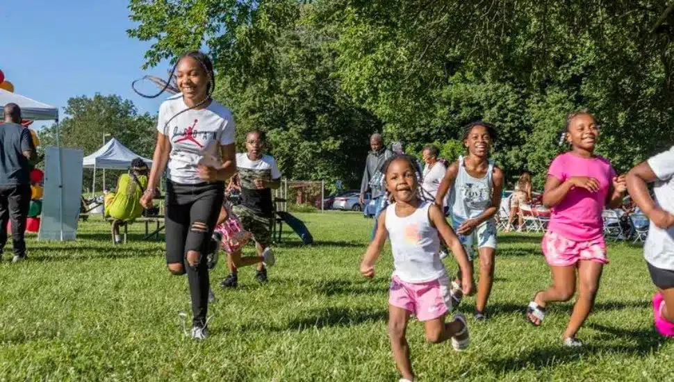 A group of Black children running on a lawn outside