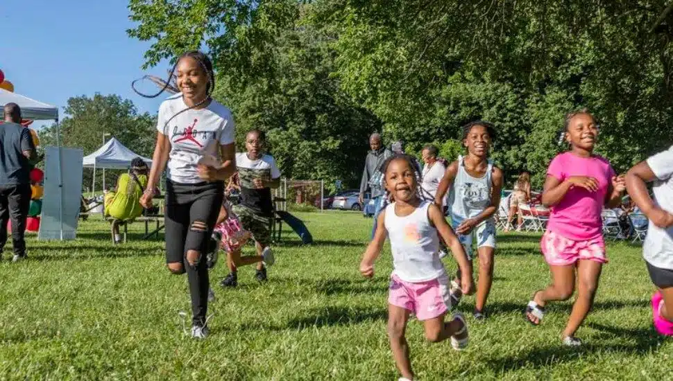 A group of Black children running on a lawn outside