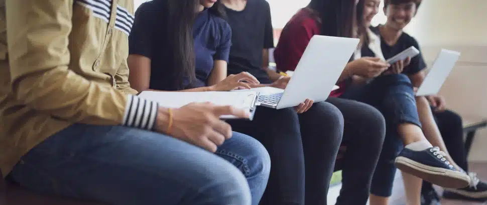 College students sitting in a row working on lap top computers