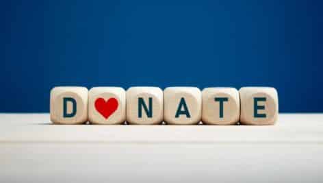 The word donate on wooden blocks with a heart icon against blue background.