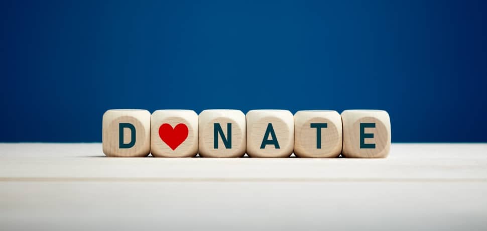 The word donate on wooden blocks with a heart icon against blue background.