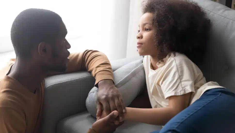 A father talking gently to his seated daughter