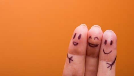 Three fingers side by side with happy faces and hugging arms drawn on them