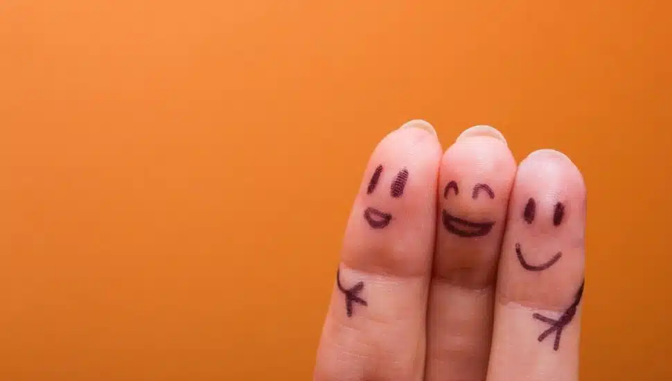 Three fingers side by side with happy faces and hugging arms drawn on them