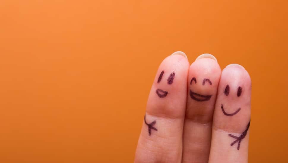 Three fingers side by side with happy faces and hugging arms drawn on them