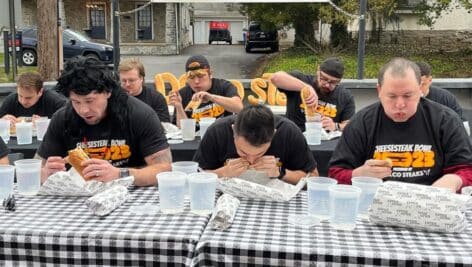 Contestants eat cheesesteaks at tables at the Marple Public House to see who can eat the most cheesesteaks in 10 minutes