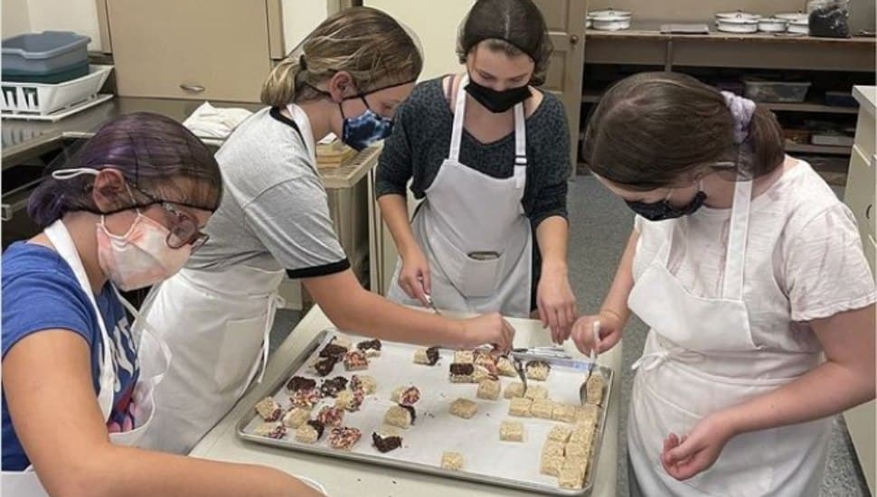 Kids gather around a tray of baked goods they made