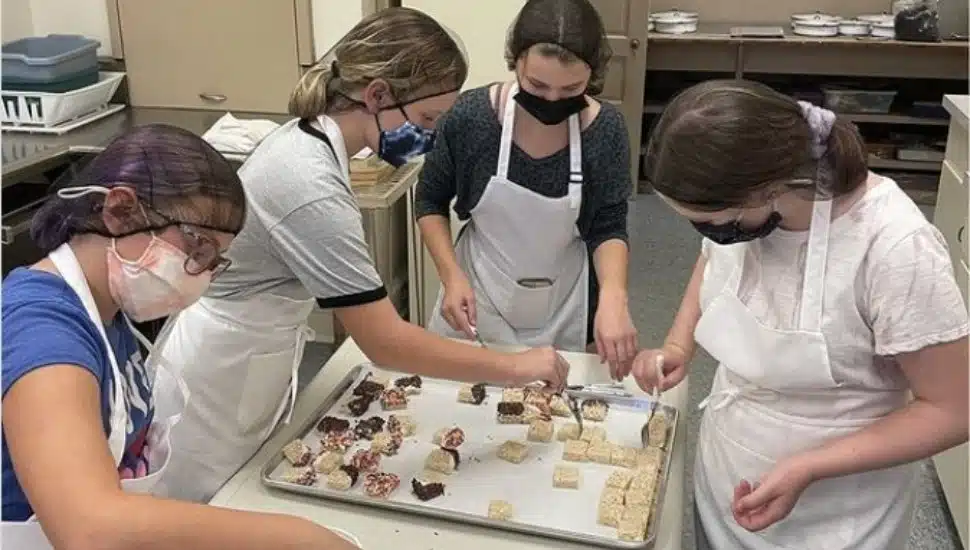 Kids gather around a tray of baked goods they made
