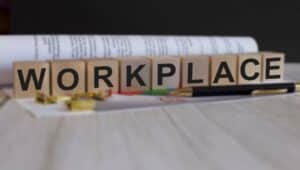 A wooden block desk sign spelling out 'workplace'