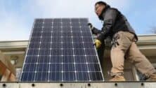 John Y.K. Lee of Havertown carries a solar panel that's going on is roof