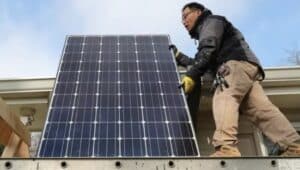 John Y.K. Lee of Havertown carries a solar panel that's going on is roof