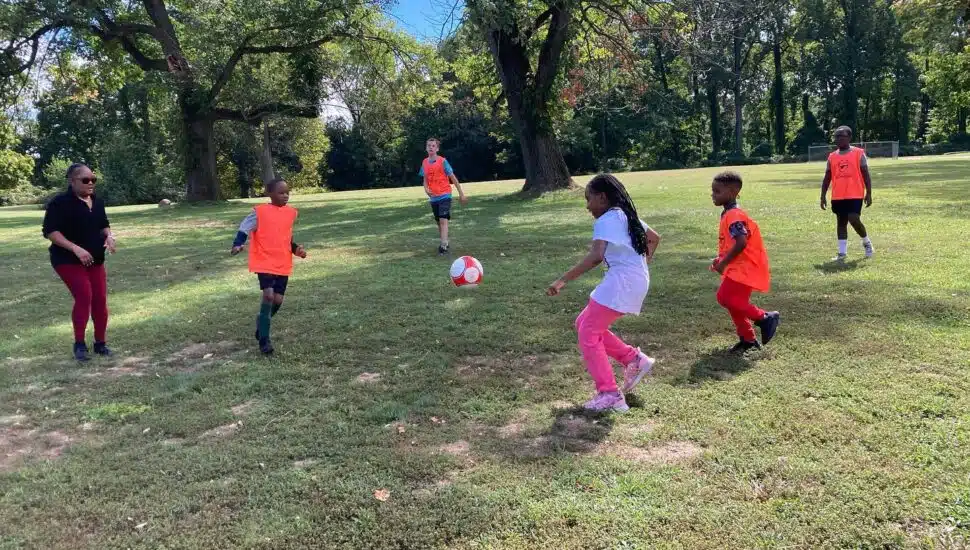 Kids play some soccer on the grass in a park
