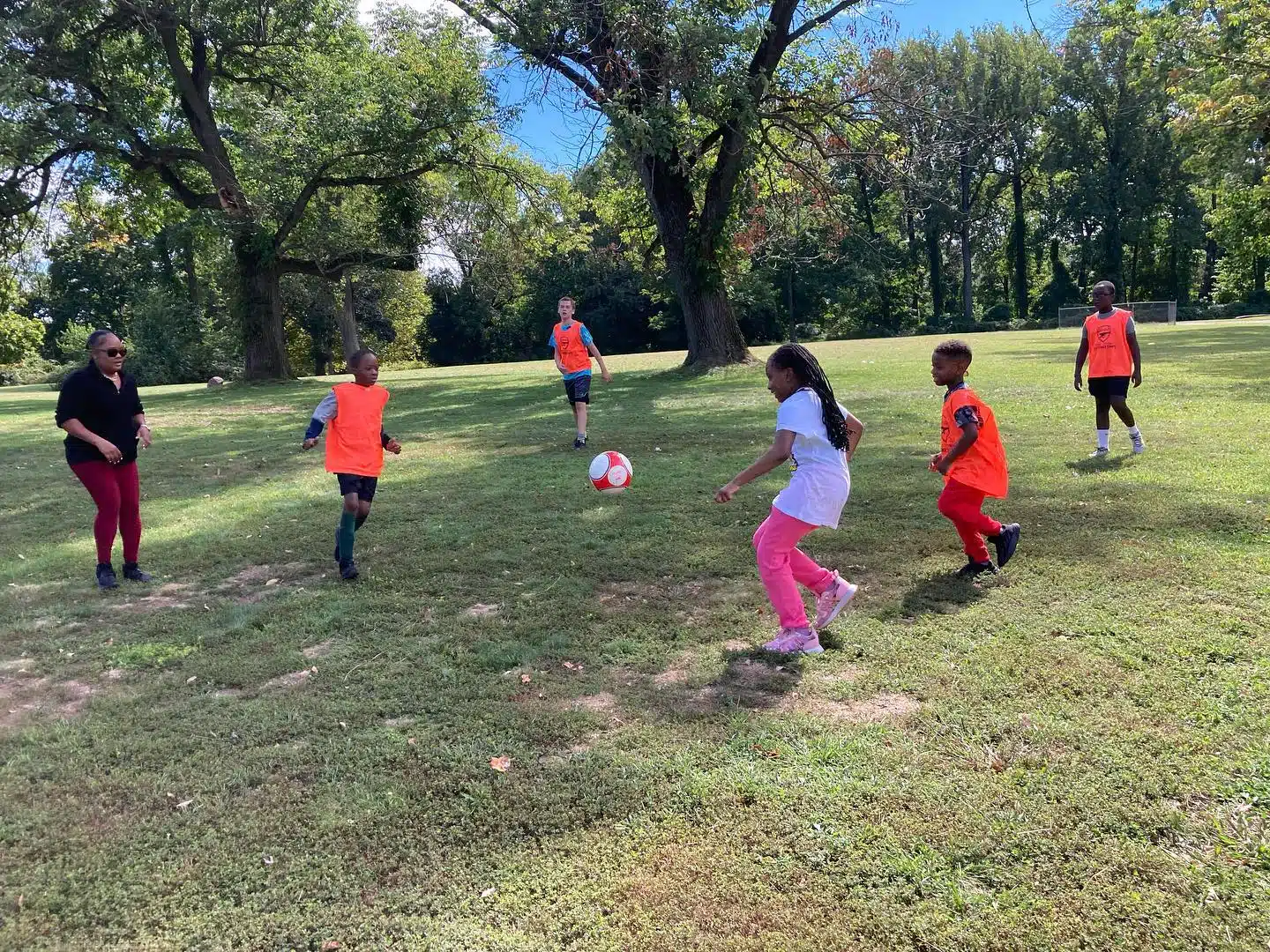 Kids play some soccer on the grass in a park