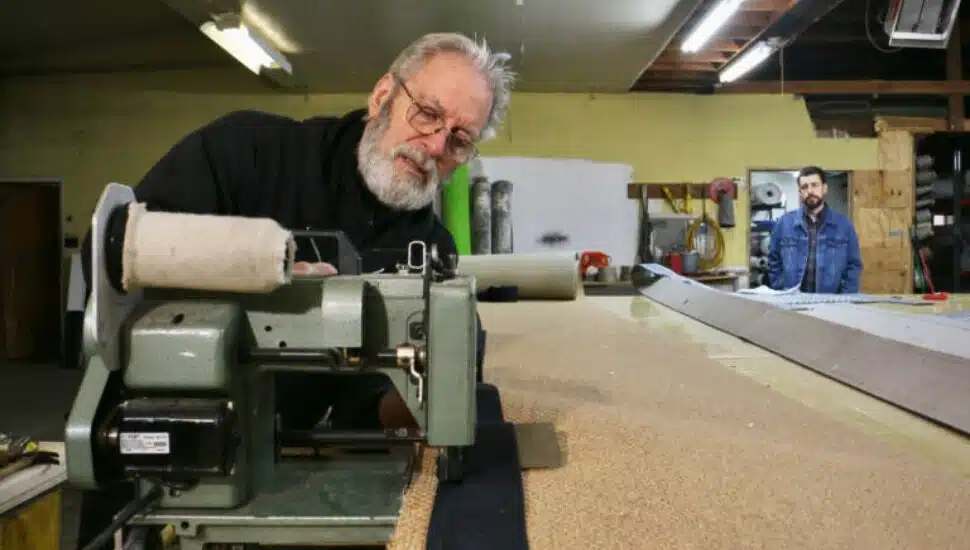 Jerry Amadio works on a rug border while his son, David, watches.