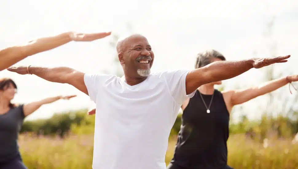 A group of men and women are outdoors practicing exercise yoga