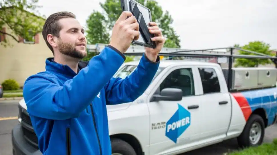 A Power Home Remodeling employee holding up a tablet to take a photo